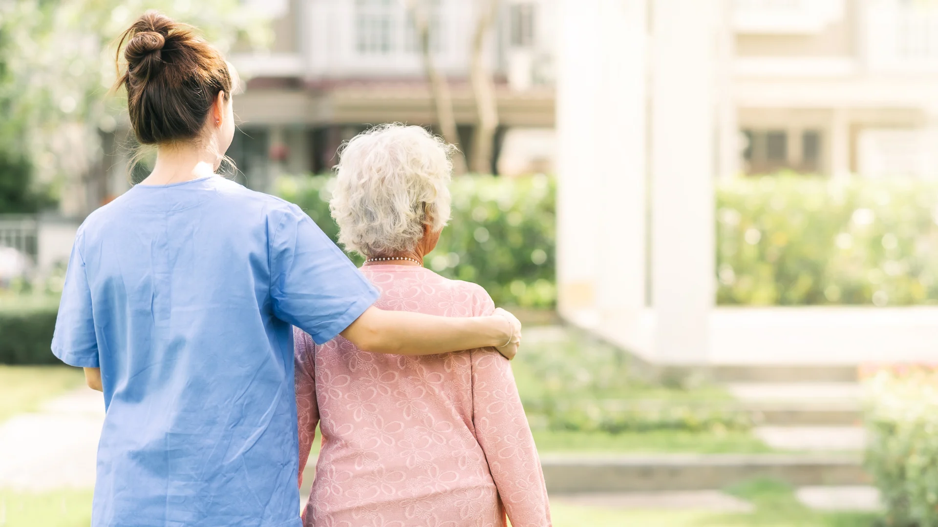 A caregiver walking outdoors with an older client