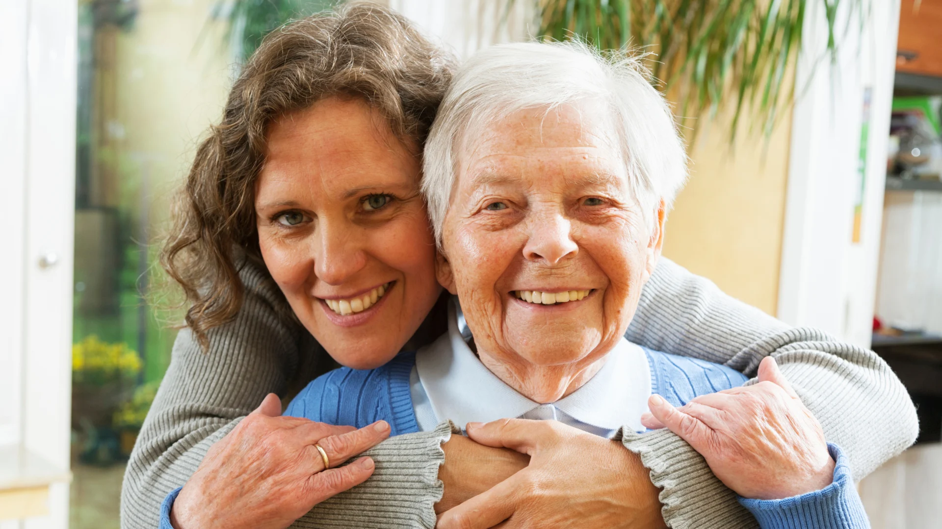 A caregiver and client sharing a warm embrace at home