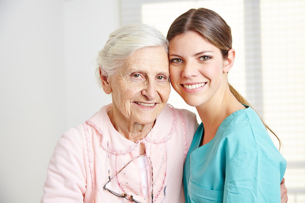 Young caregiver embracing a smiling senior woman