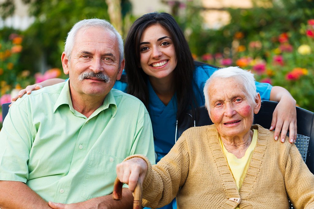 Caregiver in the garden with a senior woman and her adult son
